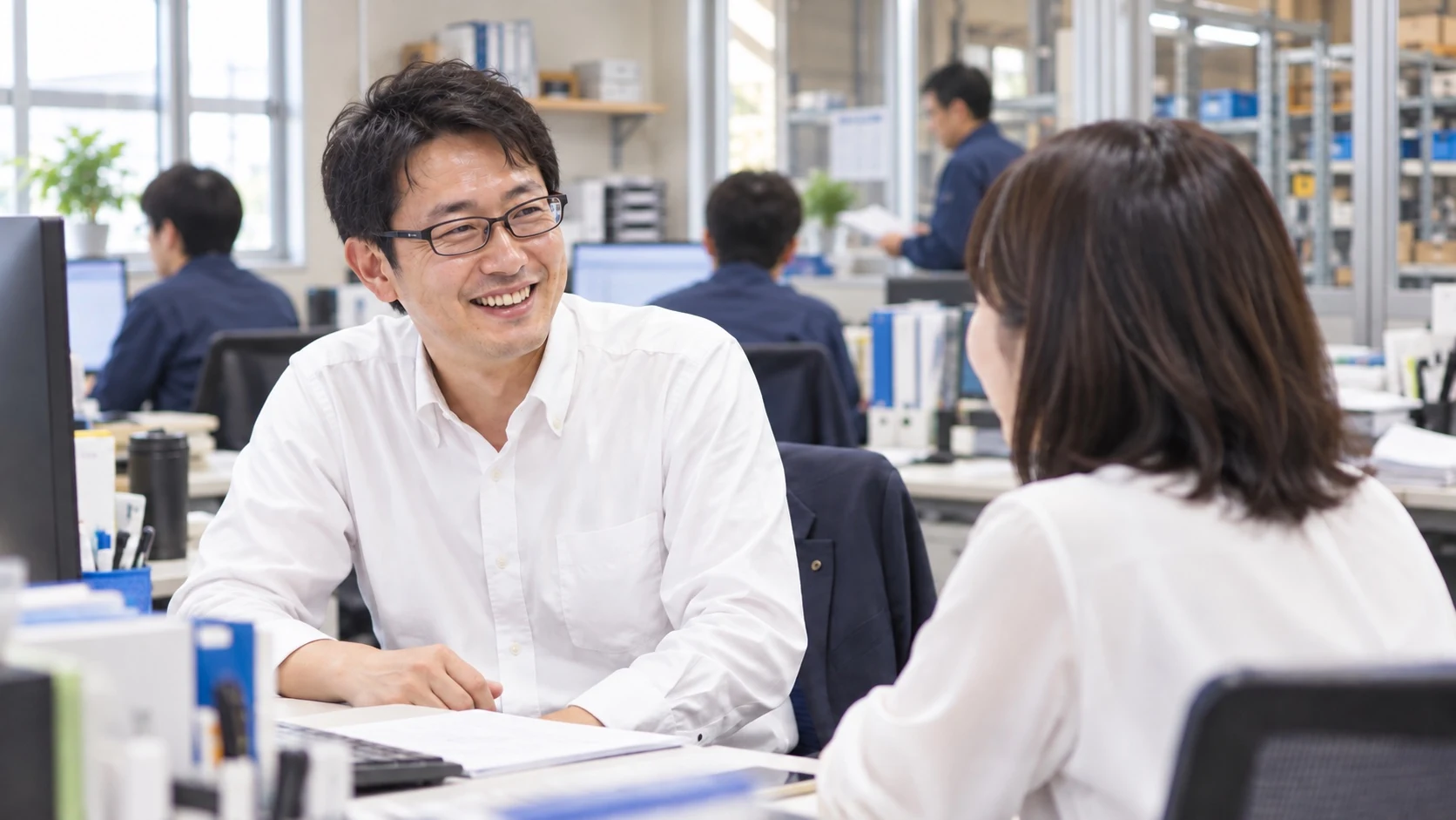 事務所で笑顔で話し合う社員たち